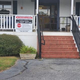 A view of the entrance to a building with stairs and a prominent sign.