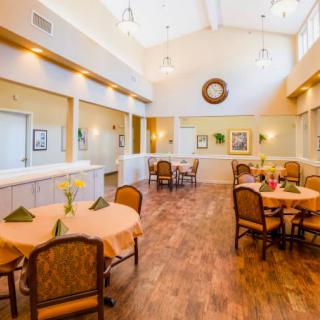 A spacious and well-lit dining area with neatly arranged tables and chairs, featuring a warm and inviting interior design.