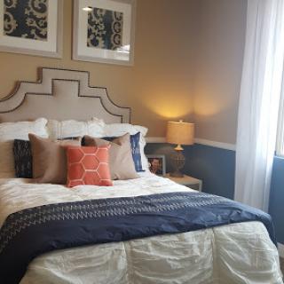 A cozy and elegantly designed bedroom featuring a stylish bed with decorative pillows and warm lighting.