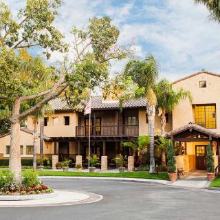 A residential building surrounded by trees and a circular driveway.