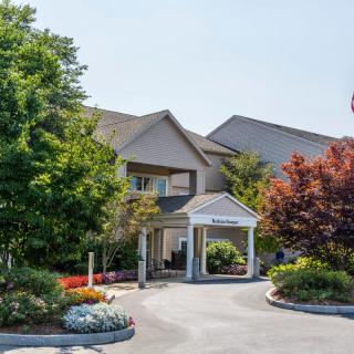 A building with a landscaped entrance surrounded by trees.