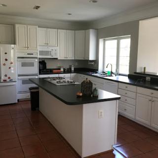 A spacious and modern kitchen featuring white cabinetry and black countertops, illuminated by natural light.