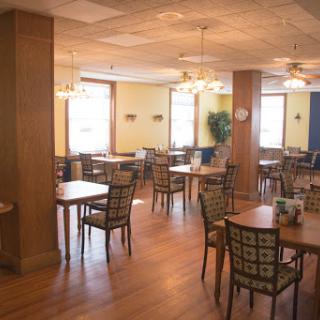 A spacious and well-lit dining area with wooden tables and chairs, ready for guests.