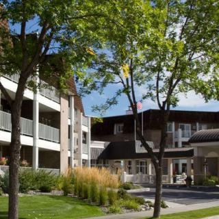 A modern building surrounded by lush greenery and trees on a clear day.