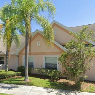 A charming suburban house with palm trees and a small garden on a sunny day.