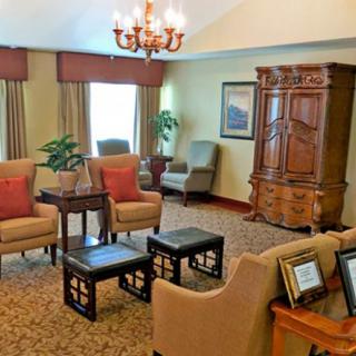 A cozy living room with comfortable armchairs, a wooden cabinet, and elegant decor.