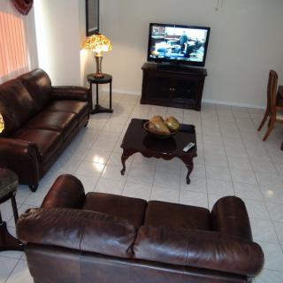 A cozy living room with leather sofas, a wooden coffee table, and a TV.