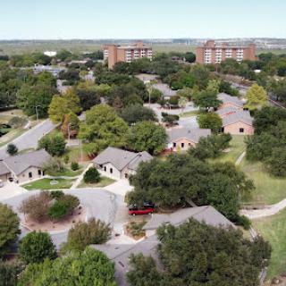 Aerial view of a suburban neighborhood featuring winding roads, residential houses, and abundant greenery.