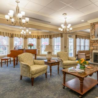 A beautifully decorated living room featuring elegant chandeliers, a warm fireplace, and comfortable seating in a traditional style.