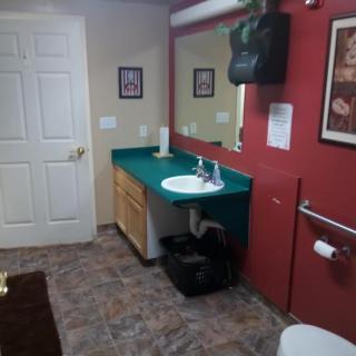A well-maintained bathroom with a sink, mirror, and decorative red walls.
