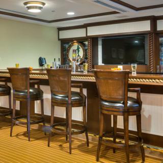 A cozy bar interior with wooden stools lined up at the counter.