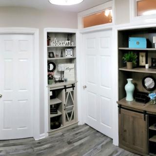 A cozy room with white doors and decorative shelves filled with various items.