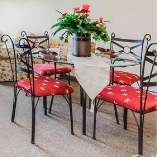 A cozy dining area with a decorated table and four chairs featuring red cushions.