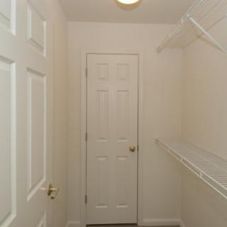 An empty closet with white doors and built-in shelves.