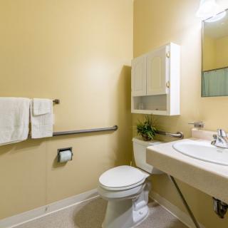A modern bathroom with a toilet, sink, and mirror against beige walls.