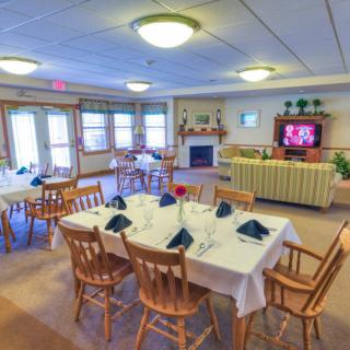 A cozy dining area with neatly arranged tables, chairs, and a fireplace, complemented by a television for entertainment.