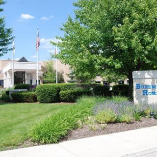 A well-maintained building surrounded by greenery and a clear blue sky.
