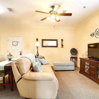 A cozy living room with a comfortable sofa, television, and ceiling fan.