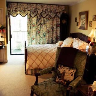A cozy bedroom with classic decor, featuring a comfortable bed and an upholstered armchair by the window.