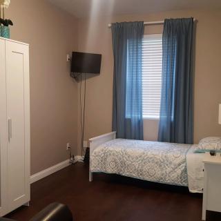 A cozy bedroom with a single bed, wardrobe, and wall-mounted TV.
