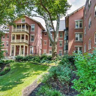 Brick residential building surrounded by lush greenery and landscaping.