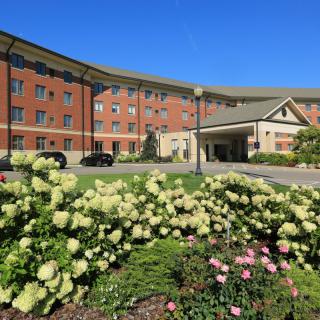 A hotel exterior with beautiful landscaping and flowers under a clear blue sky.
