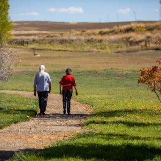Two individuals enjoying a walk along a scenic pathway in a sunny park.
