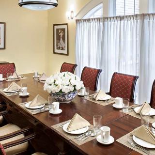 An elegantly set dining table with red chairs and a centerpiece of white flowers.