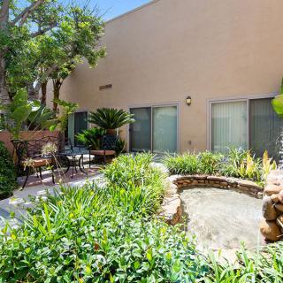 A peaceful garden patio with lush greenery and a small pond, offering a tranquil outdoor seating area.