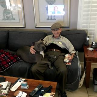 A man relaxing on a sofa with a friendly dog.