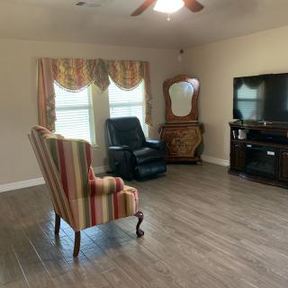 A cozy living room with a striped armchair, recliner, and entertainment center.