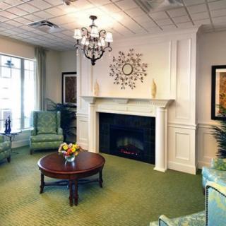 A cozy living room with a fireplace, elegant chandelier, and comfortable seating area.