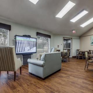 A cozy lounge area with comfortable seating and a large television, illuminated by natural light from overhead skylights.