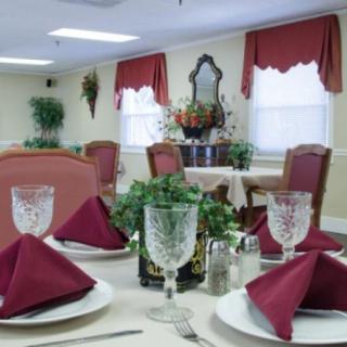 Elegant dining room with neatly set tables and red napkins.