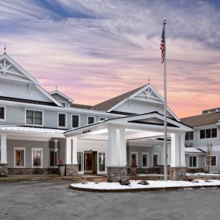 A large building with an elegant entrance at sunset, featuring an American flag and a picturesque sky.