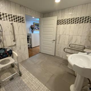 A spacious and accessible bathroom designed with safety in mind, featuring grab bars and a shower chair.