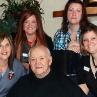 A group of five people posing together indoors with smiles.