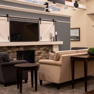 A modern living room with sofas, a fireplace, and a mounted television.
