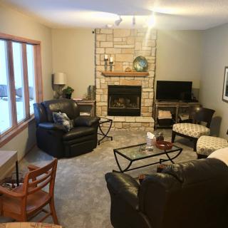 A cozy living room featuring a stone fireplace, comfortable seating, and a television.