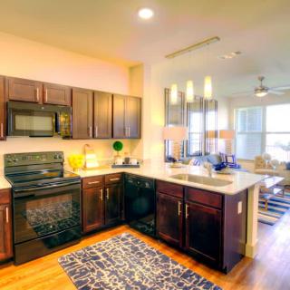 A modern kitchen with dark wooden cabinets and appliances in an open apartment layout.