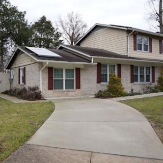 A charming two-story house featuring a well-maintained driveway and solar panels on the roof.