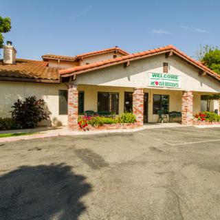 An exterior view of a clinic building with a parking area in front.