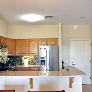 A modern kitchen with wooden cabinets and a sleek refrigerator.
