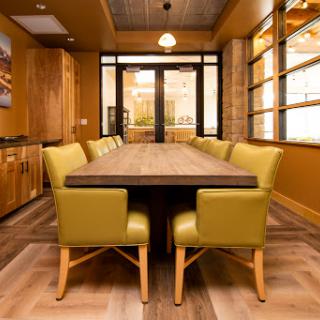 A modern dining room featuring a large wooden table surrounded by stylish yellow-green chairs, illuminated by natural light.