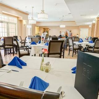 An elegant dining room with neatly arranged tables and chairs, featuring blue napkins.