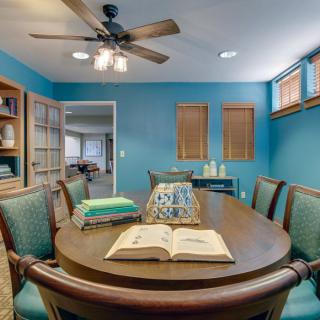 A cozy dining room with blue walls, featuring a wooden table surrounded by chairs and an open book.