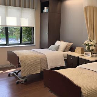 A well-designed hospital room featuring two patient beds and ample natural light.