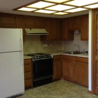 A kitchen with wooden cabinets, a white refrigerator, and a black stove.
