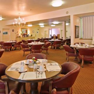 An inviting dining area with neatly arranged tables and chairs, featuring elegant place settings and soft lighting.