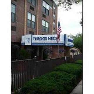 Entrance to a building with a 'Throgs Neck' sign and an American flag.